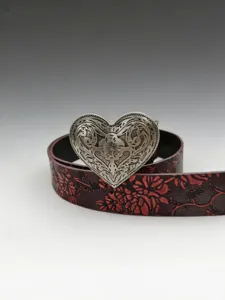 Detailed view of western vintage floral embossed leather belt with ornate silver heart buckle.