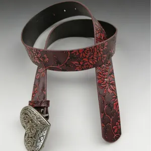 Vintage women's embossed leather belt with western heart metal buckle and red floral pattern.
