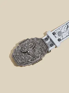 Close-up detail of western cowboy leather belt with antique silver bull skull buckle.