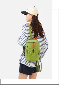 Detailed shot of wearing a compact green mini backpack with adjustable straps and front pockets.