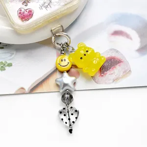 Primo piano dettagliato del grazioso ciondolo orsetto gommoso giallo con smiley e perline stella.