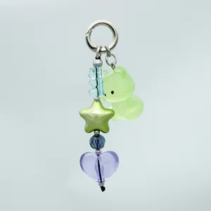 Primo piano dettagliato di un portachiavi con orsetto verde e stella, perline acriliche.