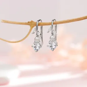 Primer plano de pendientes colgantes de plata con hojas y circonitas, diseño fino.