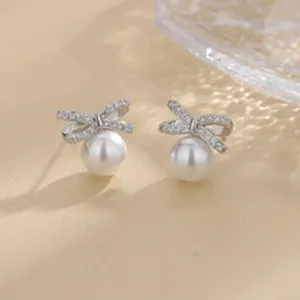 Vista detallada de pendientes de perlas con lazo de diamantes de imitación, diseño elegante.