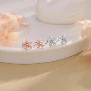 Vista detallada de delicados pendientes de botón de flor de circonita oro y plata.