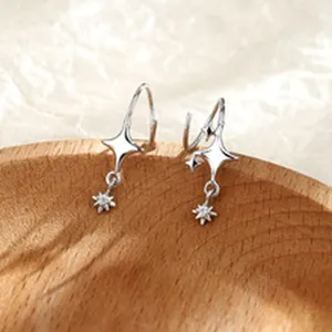 Primer plano detallado de exquisitos pendientes colgantes de plata con estrella, diseño elegante.