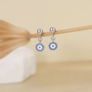 Vista detallada de aretes de plata de mal de ojo con dijes redondos de circonita cúbica.