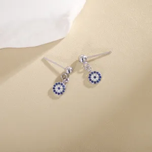 Vista detallada de pendientes de botón de mal de ojo de plata con circonitas azules y blancas.