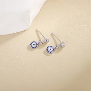 Detalle de pendientes de circonita mal de ojo, diseño geométrico cristal azul blanco.