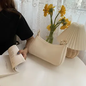 Minimalistische beige Baguette-Umhängetasche in gemütlicher Zimmeratmosphäre mit Blumen.
