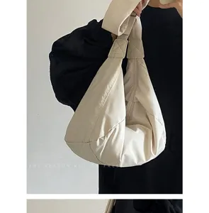 Nahaufnahme der stilvollen beigen Puffer Schultertasche mit weicher gesteppter Textur.