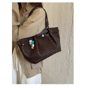 Dettaglio di borsa tote intrecciata marrone con ciondolo di perline, stile retrò chic.