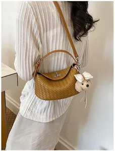 Detailed shot of retro woven shoulder bag with chic metal lock and cute bear charm pendant.
