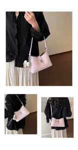 Detailed view of the pink stylish shoulder bag with lock closure and cute bear pendant charm.