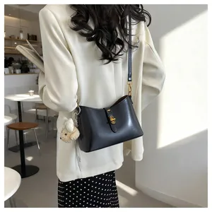 Stylish minimalist black leather shoulder bag with chic metal lock and cute plush charm.