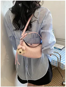 Detail view of the elegant pink woven underarm shoulder bag with cute bear pendant.
