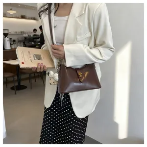 Stylish brown leather shoulder underarm bag with metal lock and cute bear charm for women.