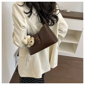 Chic dark brown underarm shoulder bag for women, featuring a cute bear pendant and clasp.