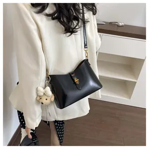 Detailed view of black leather shoulder underarm bag with gold lock and cute bear charm.