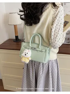 Detailed view of the mint green litchi pattern leather Kelly handbag with a cute plush charm.