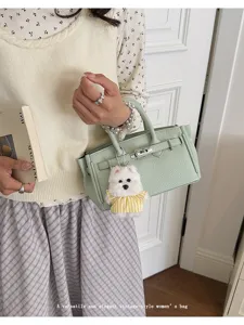 Chic light green leather Kelly bag with cute plush dog pendant, elegant vintage handbag.