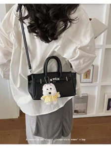 Close-up detail of the elegant black leather women handbag styled with cute plush dog pendant charm.