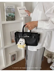 Classic black litchi grain women handbag with elegant metal hardware and cute dog pendant.