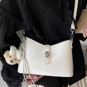 Minimalist white leather shoulder underarm bag with chic metal lock and cute bear pendant.