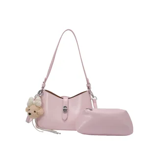 Stylish pink PU leather shoulder bag with matching clutch and cute bear pendant for women.