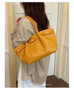 Vista dettagliata della borsa tote elegante in pelle intrecciata gialla a spalla.