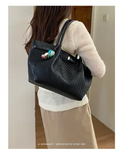 Vista dettagliata della borsa tote in pelle intrecciata nera con elegante ciondolo in pietra.