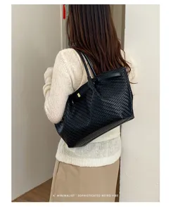 Vista di dettaglio della borsa tote in pelle intrecciata nera, stile spalla, estetica retrò.
