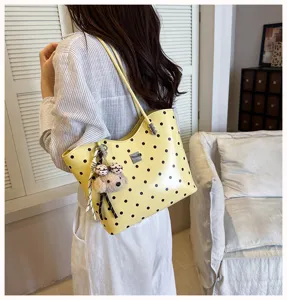 Detail shot of women's yellow polka dot shoulder tote bag with cute plush puppy pendant.