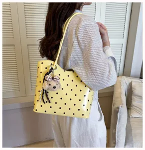 Yellow polka dot shoulder tote bag detail view, featuring a cute puppy plush pendant charm.