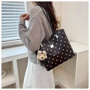 Detail view of the black and white polka dot tote shoulder bag with cute puppy plush charm.