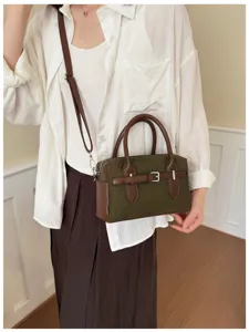 Close-up detail of dark green Boston shoulder bag with brown leather trim and metal buckle.