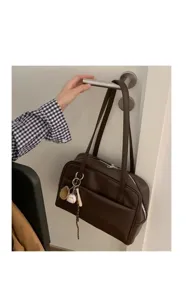 Detail view of brown retro shoulder bag with baseball charm, solid color minimalist design.