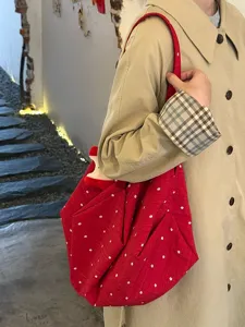Vista detallada del bolso de lona roja con estampado floral, gran capacidad y estilo casual.