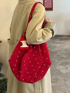 Vista detallada del bolso tote de lona floral roja con colgante de felpa de manzana y estilo diario.