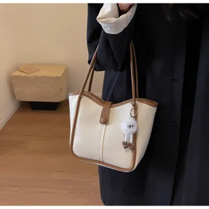 Vista dettagliata di una elegante borsa tote bicolore in pelle PU con un grazioso ciondolo.