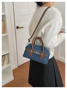 Detail view of stylish denim Boston shoulder bag with brown leather trim and metal lock.