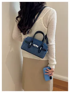Stylish denim Boston handbag with black leather trim, top handles and shoulder strap.
