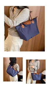 Detailed view of women's nylon travel tote bag, waterproof dumpling handbag with leather flap.