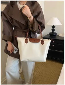 Nylon tote bag detail showing cream white fabric, brown leather handles, and front flap design.
