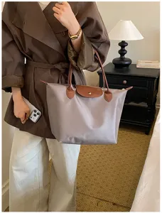 Detailed lifestyle shot of a stylish nylon folding tote handbag with brown leather flap in a chic room.
