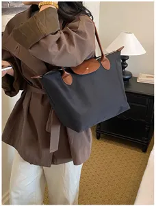 Detailed view of large capacity nylon tote bag featuring classic brown leather flap and handles.