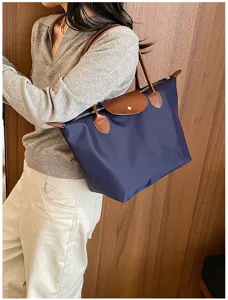 Detail view of stylish waterproof nylon shoulder tote bag in navy blue with brown leather.