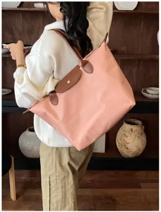 Detail shot of the pink nylon shoulder bag featuring brown leather trim and classic folding design.