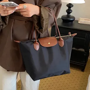 Women's large capacity nylon folding tote bag with brown leather handle and top zip closure.