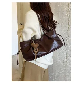 Detailed shot of retro brown slouchy shoulder bag with charm, showcasing soft leather texture.